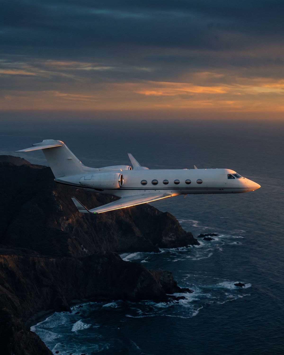 A business jet over a coastline in the late afternoon